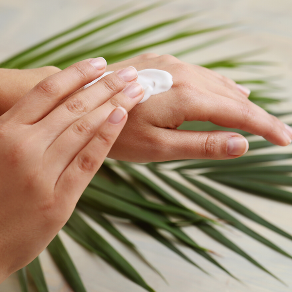 Hand putting on Camel Milk Body Lotion with Tree Leaf Background