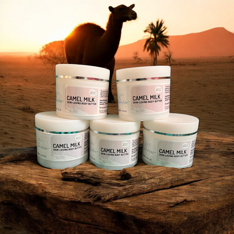 Five jars of Cammellatte Butter Lover Bundle are displayed on a log in the desert at sunset, with a camel and palm trees behind—ideal for soothing dry skin with their natural fragrance.