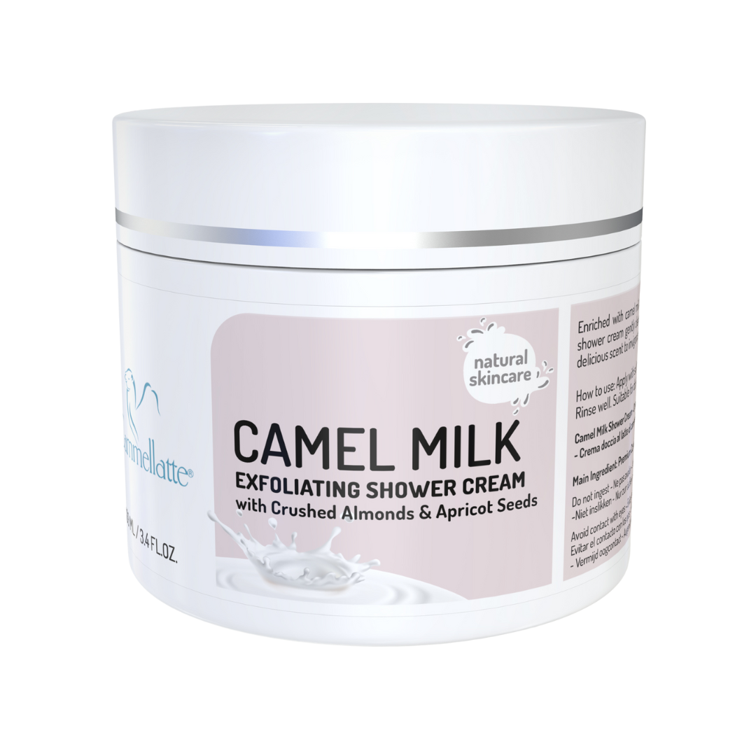 A white tub of Cammellatte Camel Milk Exfoliating Shower Cream, enriched with shea butter, crushed almonds, and apricot seeds, is labeled as natural skincare and features a milk splash with product details on the container.